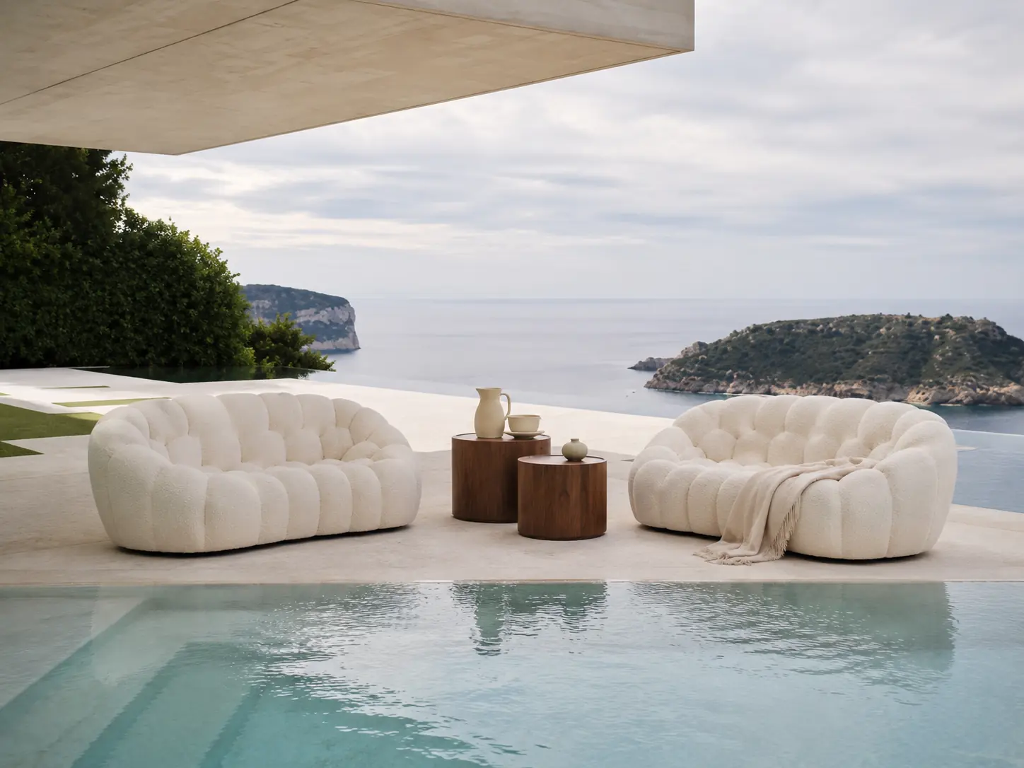Sculptural cream lounge seating beside an infinity pool overlooking the coast