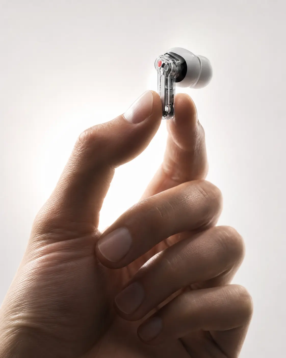 Transparent wireless earbud held close in a hand