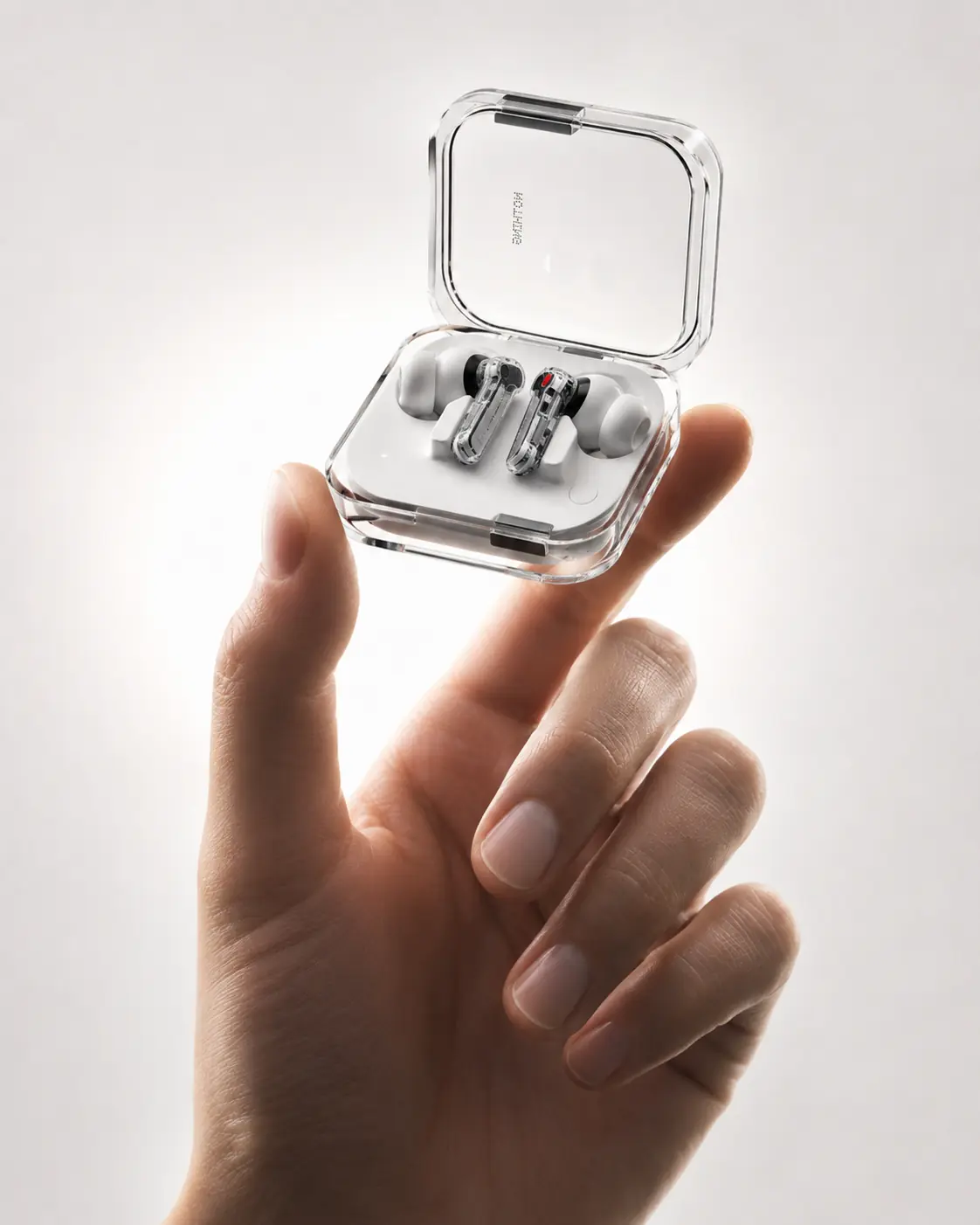 Transparent wireless earbuds and case held in a relaxed hand