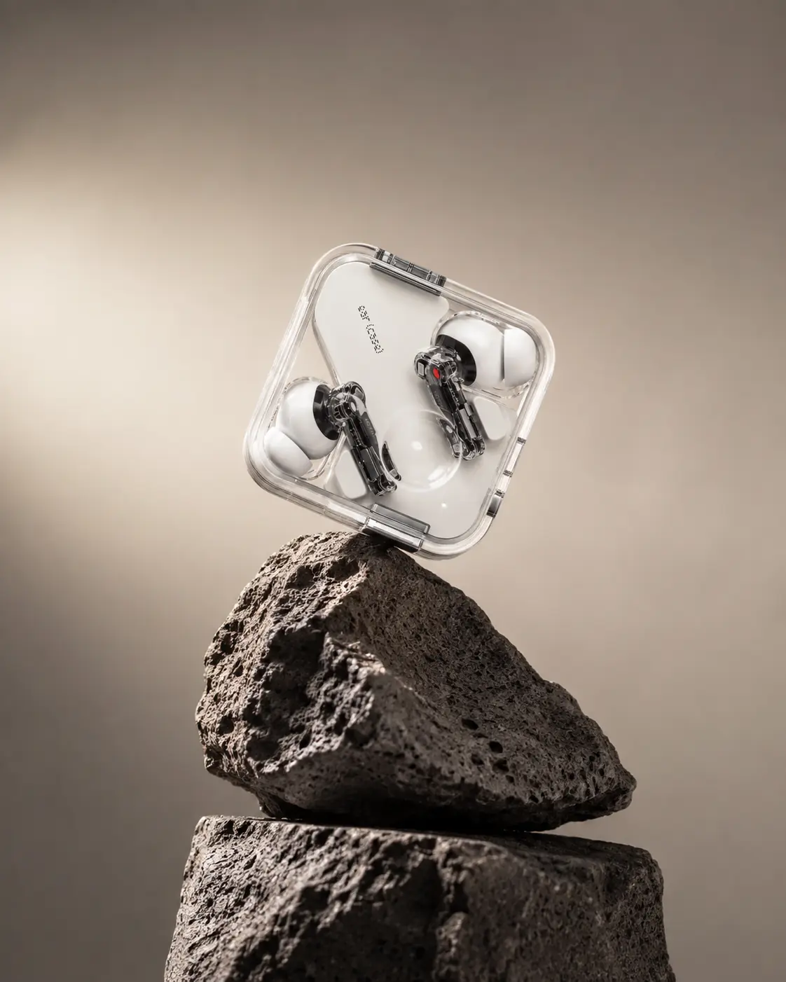 Transparent wireless earbuds balanced on sculptural volcanic stone