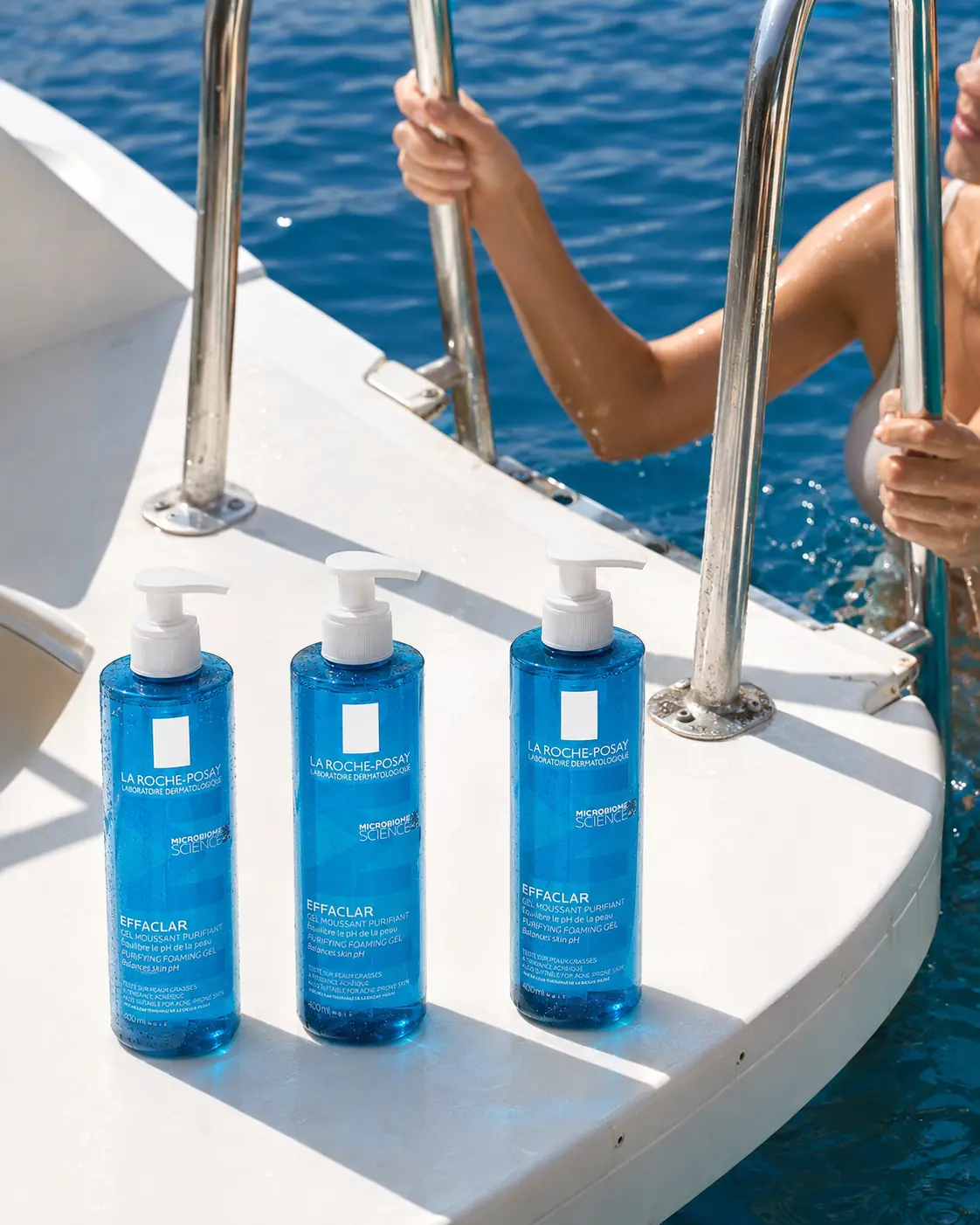Blue sunscreen bottles arranged on a white boat at the edge of the sea