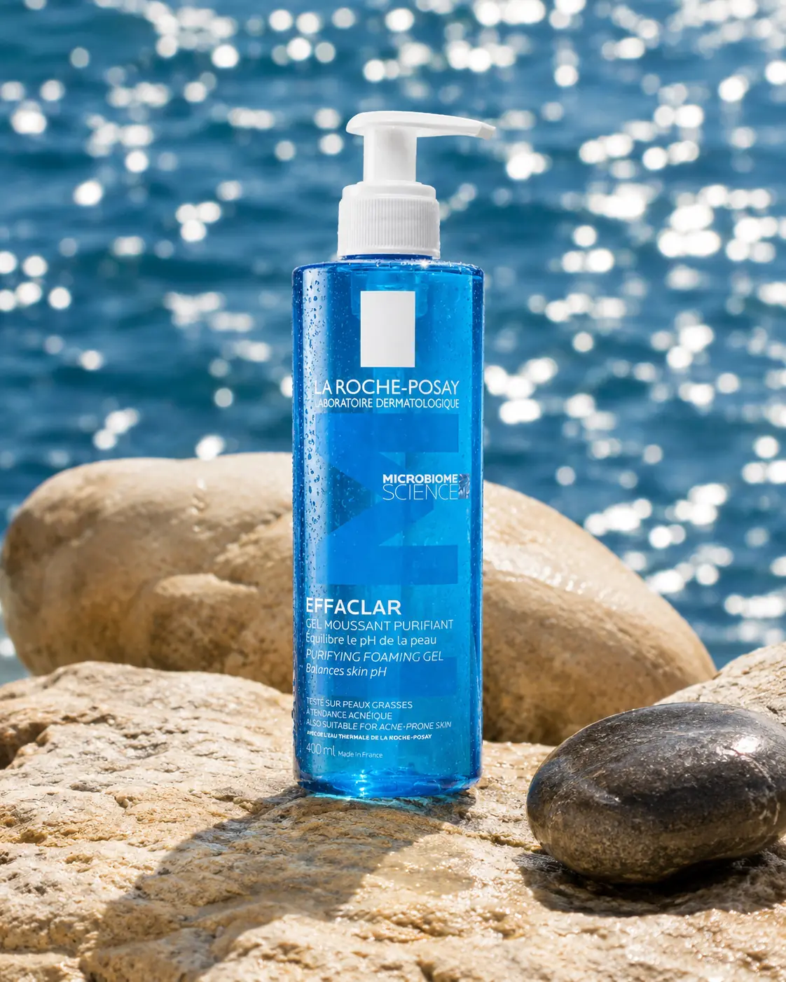 Blue sunscreen bottle arranged on sunlit shoreline stones