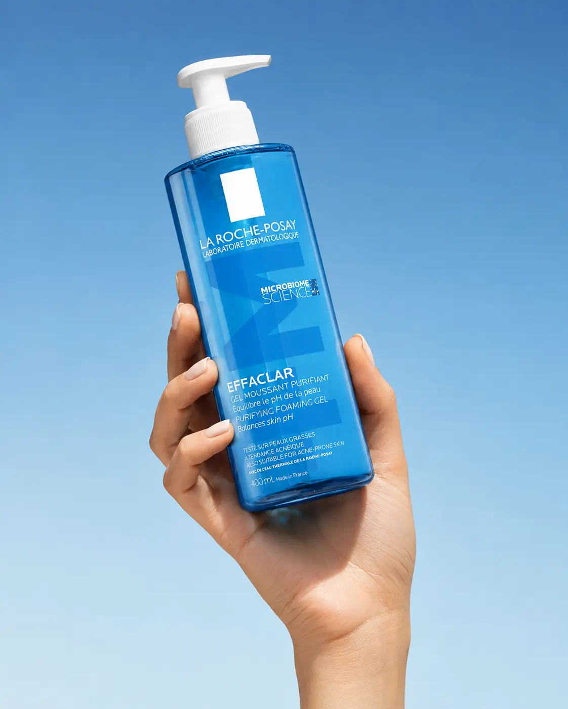 Blue sunscreen bottle held up against a clear summer sky