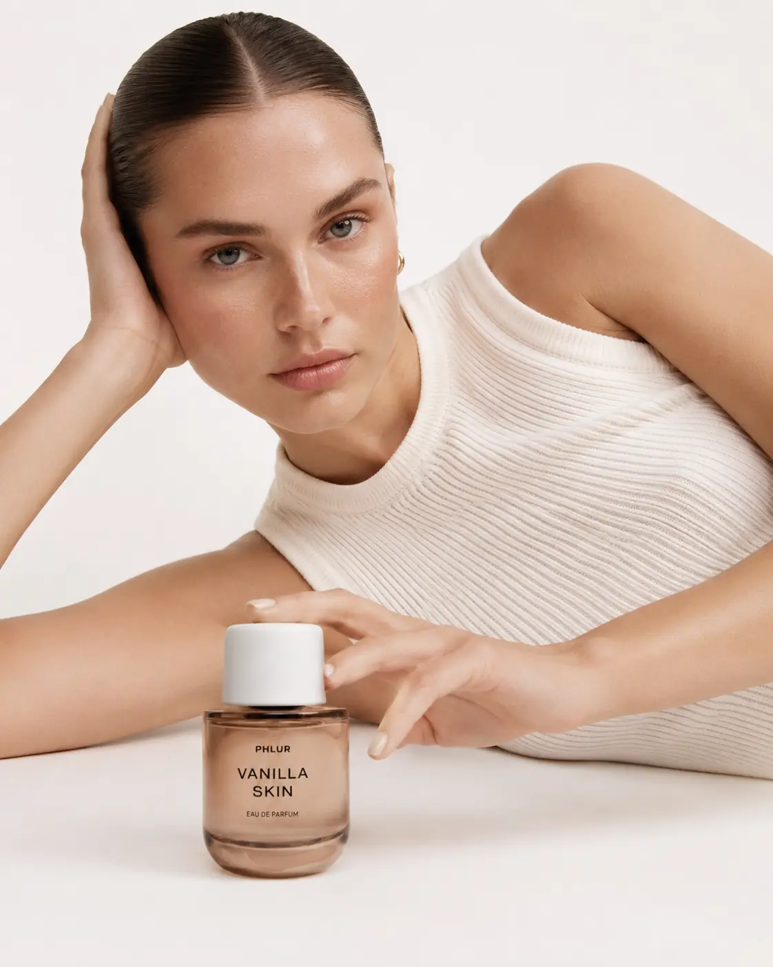 Beauty portrait with a fragrance bottle in a soft editorial setting