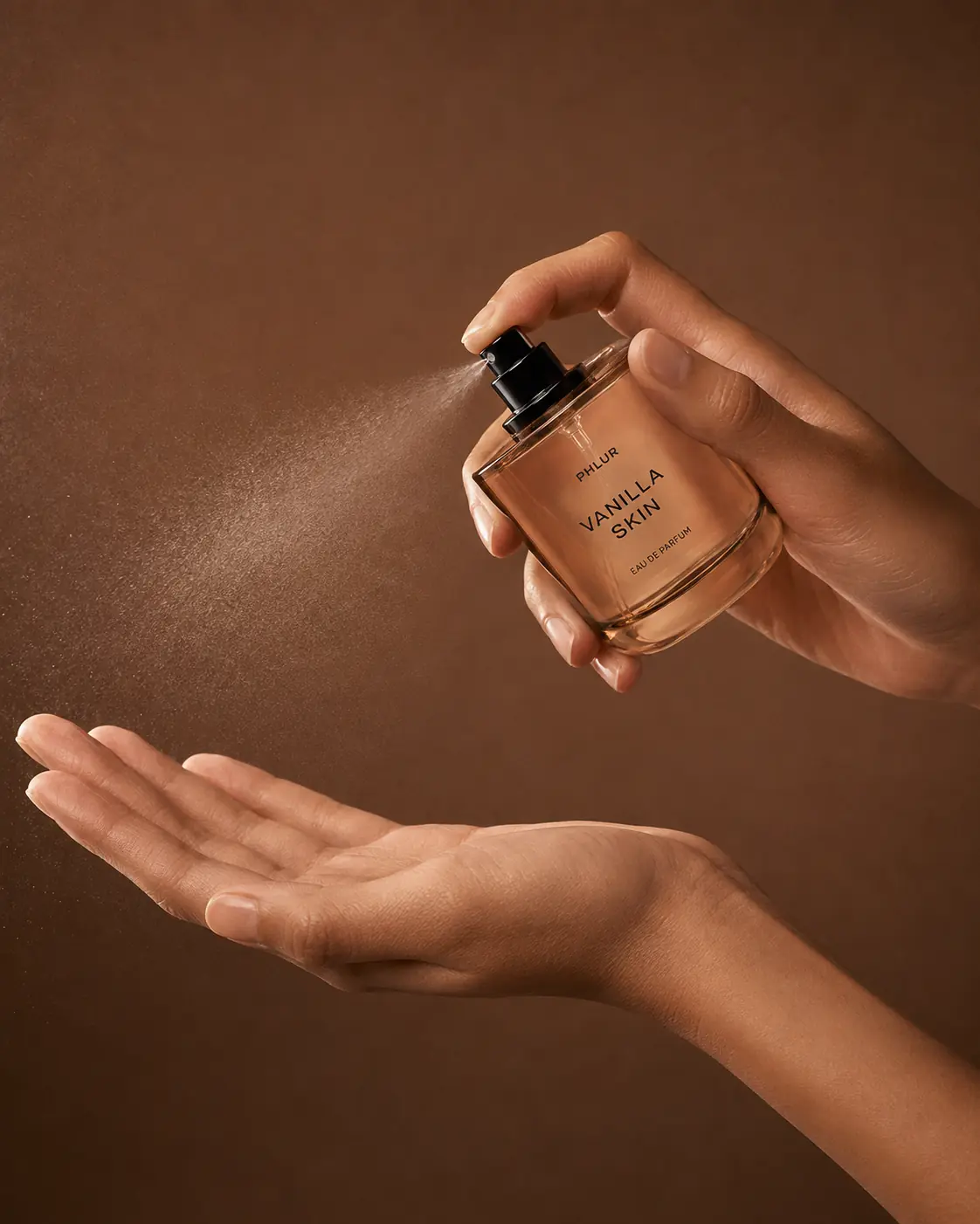 Fragrance bottle being sprayed against a warm brown background
