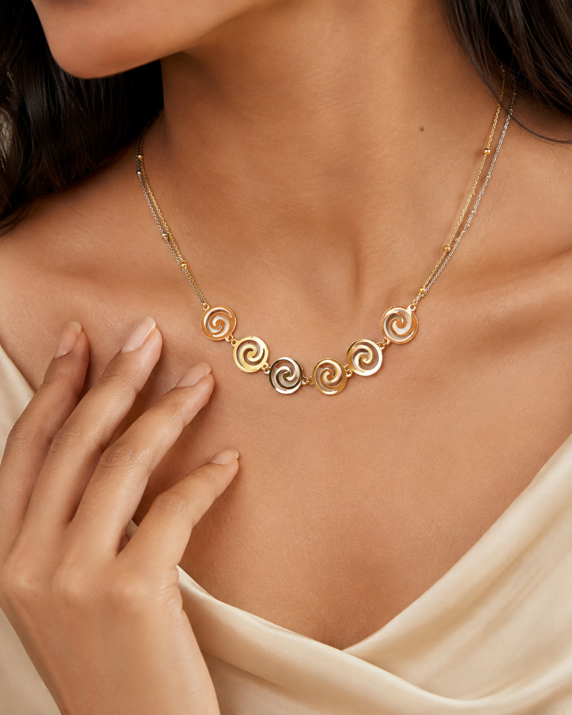 Close editorial view of a polished three-tone spiral necklace