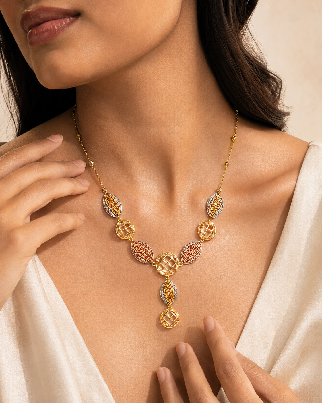 Three-tone lattice necklace styled with hands in a refined campaign composition