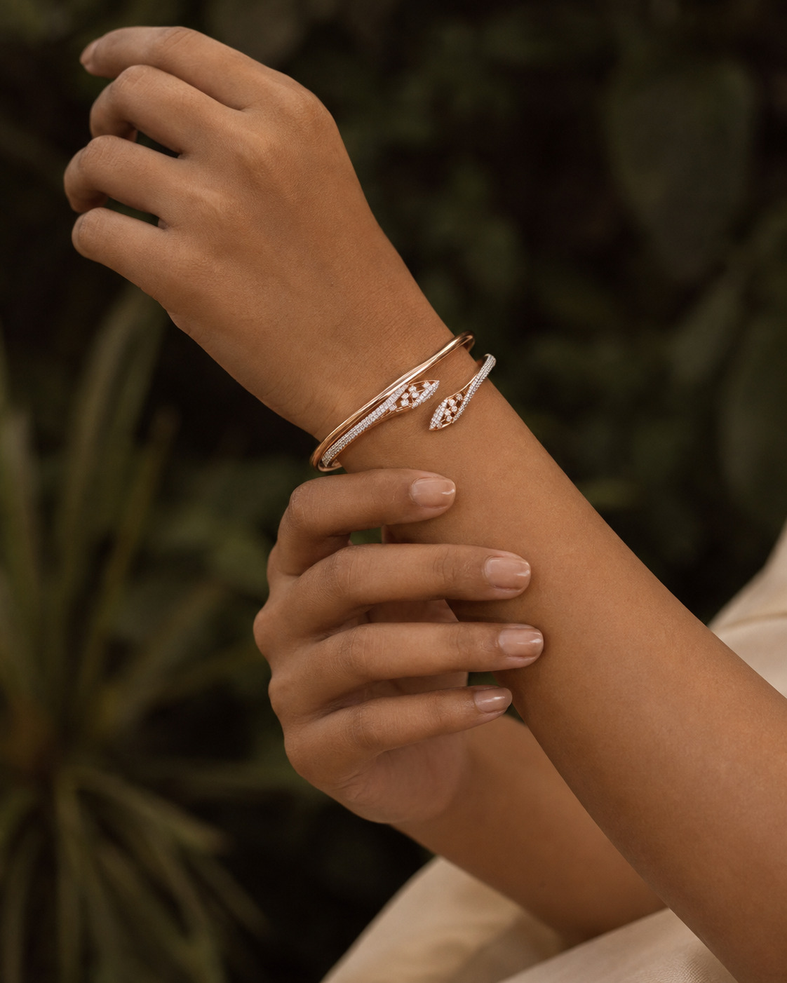 Rose-gold diamond cuff bracelet styled against a deep botanical background